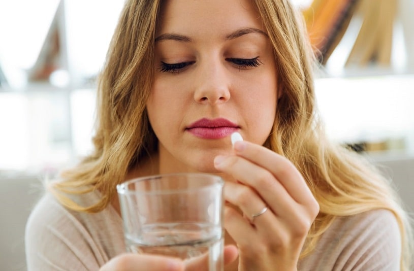 Young woman taking pills at home.