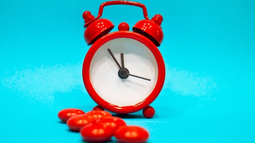 Red pills next to a clock.