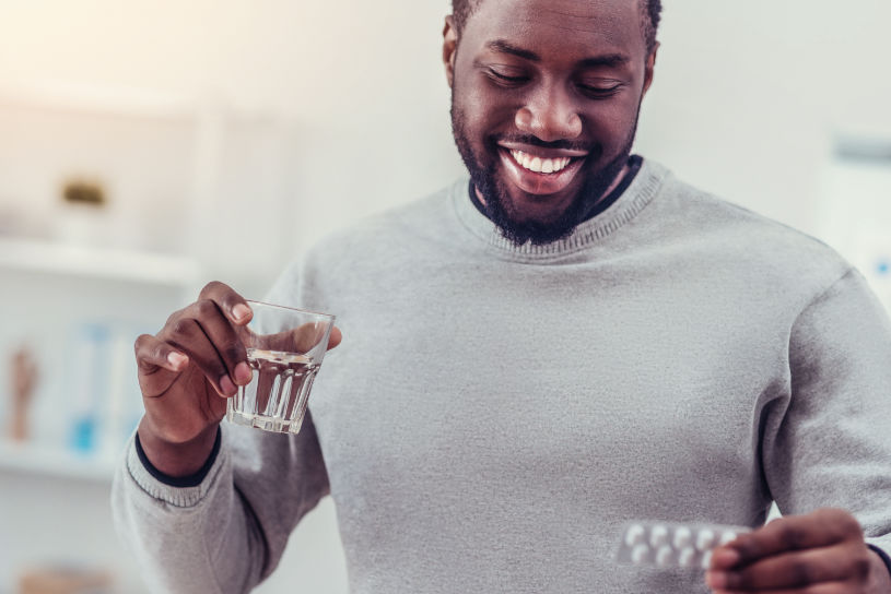 A man holds Phenobarbital pills and a glass of water.