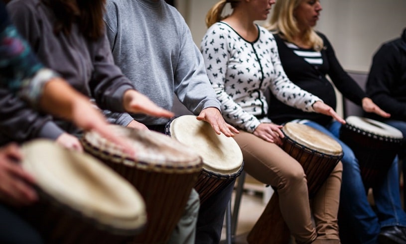 Group of people playing drums during the session.
