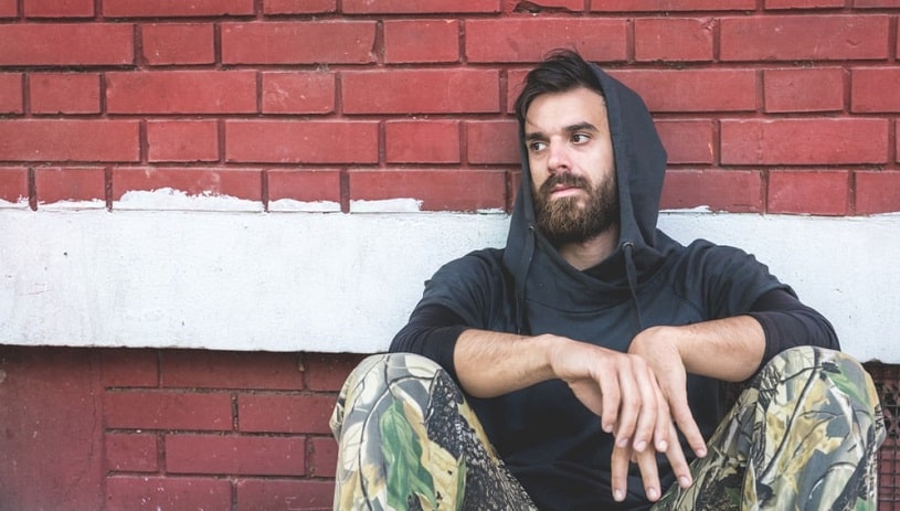 Addicted depressed man sitting on the street.