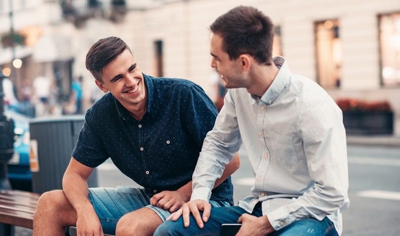 Two men are talking on the bench.