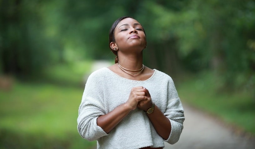 Woman praying hoping that higher power will help her.