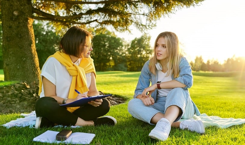 Therapist and patient discussing something outdoors in the park.