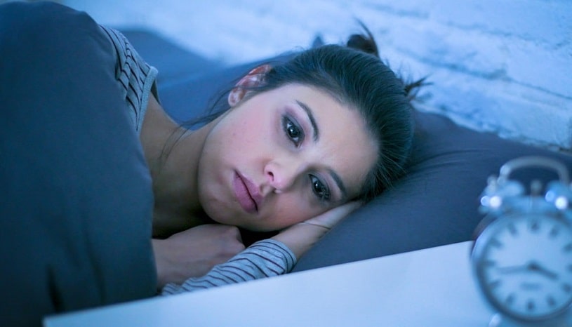 Young woman with insomnia lies in bed.