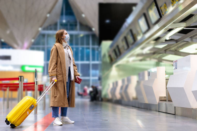 Woman with luggage stands at check-in.