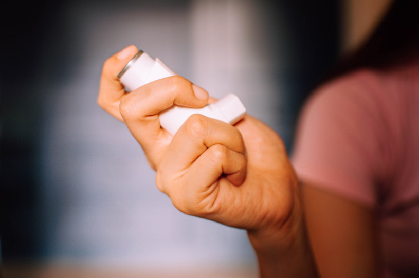A woman holds spray in her hand.