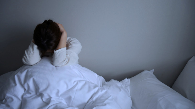 A woman in depression puts her hands over her head.