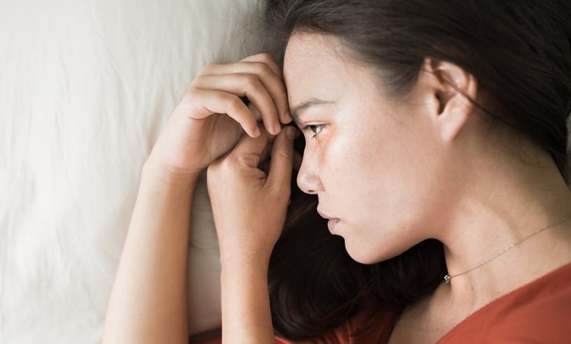 Sad woman lying in her bed.