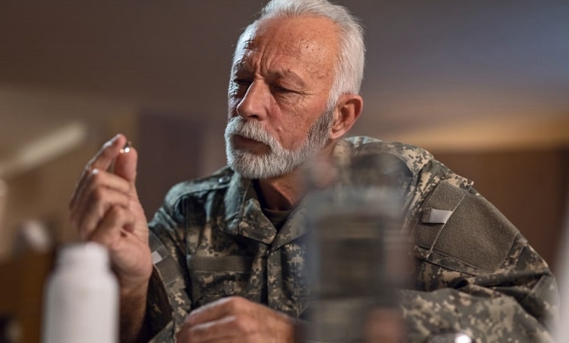 Thoughtful old veteran taking a pill.