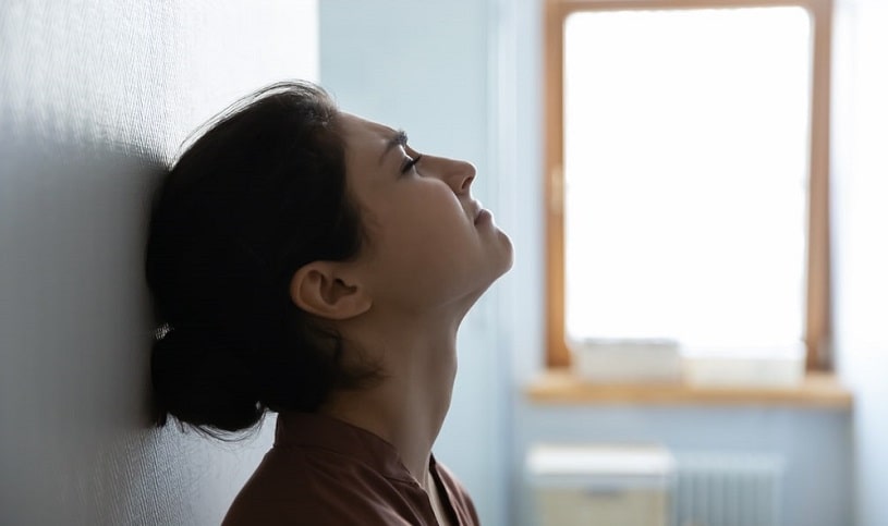 Stressed woman sitting next to the wall.