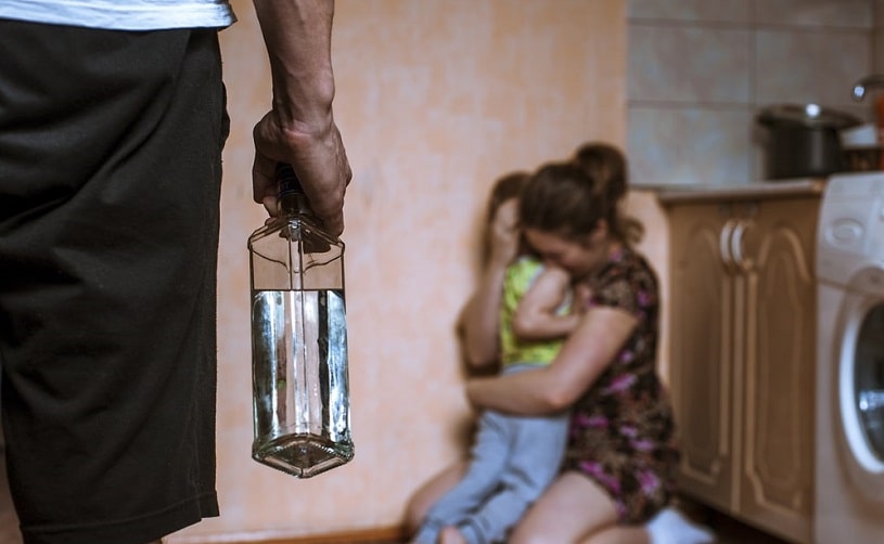 Woman covering her child from angry drunk father.