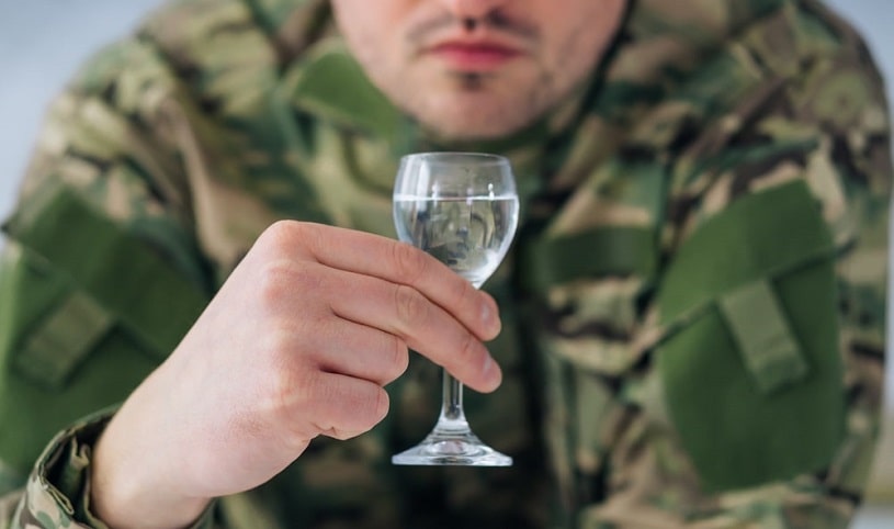 Military man holding a vodka shot.