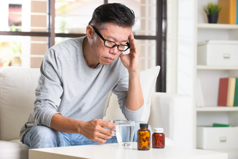 A man looks at buspar pills on the table.