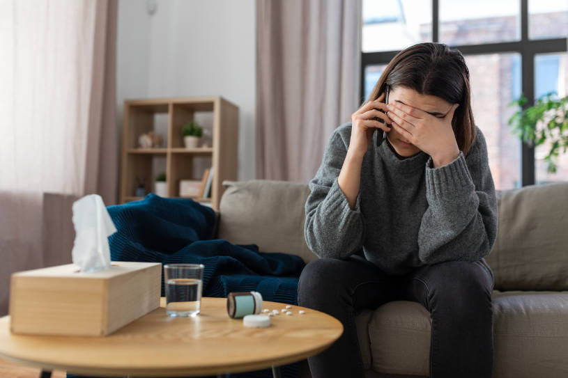 A woman with a strong headache experiences sedatives side effects and calls her doctor.
